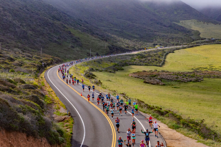 Photo of runners passing through beautiful green scenery at the Big Sur Marathon 2025