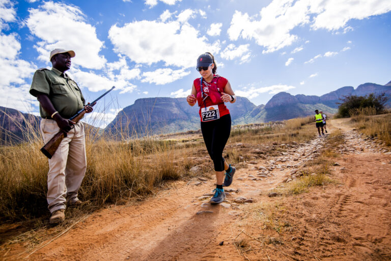 Photo of a runner passing a gamekeeper on the Big Five Marathon 2025